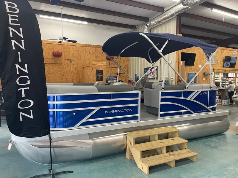 Slide: The Image of 2024 Bennington 188SVLSR pontoon boat displayed indoors with blue accents and canopy. - 1