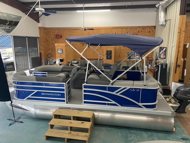 Slide: The Image of 2024 Bennington 188SVLSR pontoon boat with blue canopy in showroom. - 3