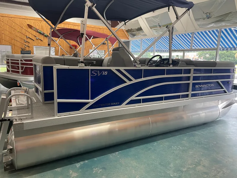 Slide: The Image of 2024 Bennington 188SVLSR pontoon boat in showroom, featuring blue exterior and canopy. - 9