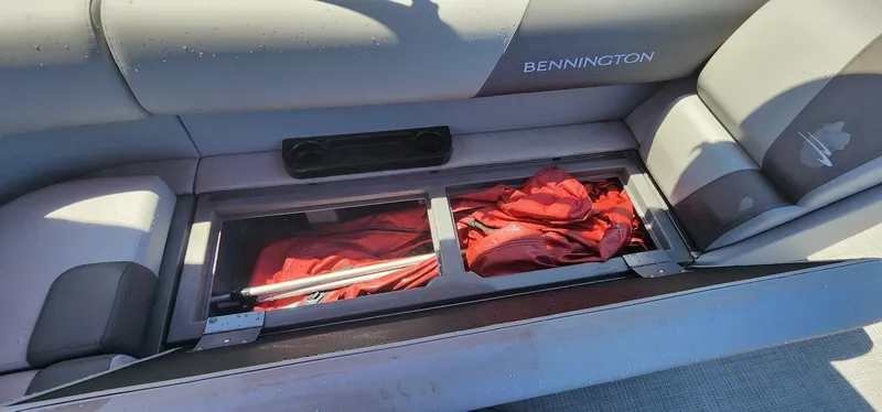 Slide: The Image of 2024 Bennington 20SVFSR boat seat storage with red life jackets. - 18