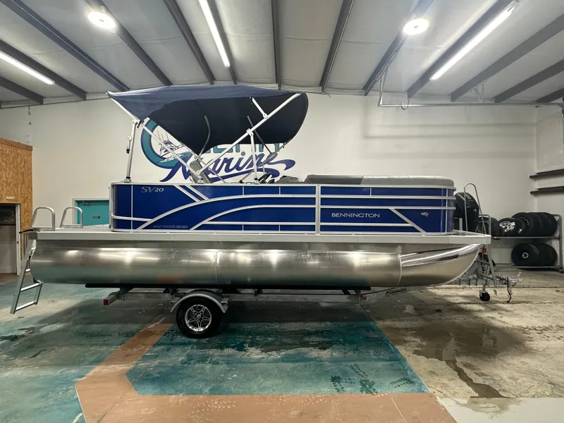 Slide: The Image of 2024 Bennington 20SVLSR pontoon boat in showroom, blue with canopy. - 9