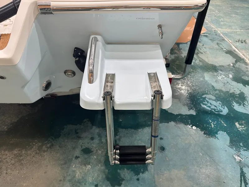 Slide: The Image of 2025 Key West 230BR boat swim platform with foldable ladder on wet surface. - 14