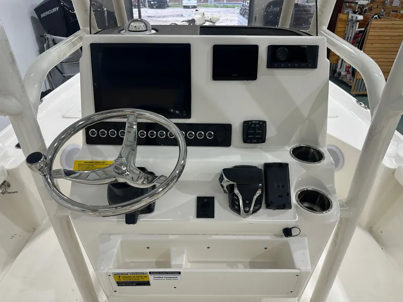 Slide: The Image of 2025 Key West 230BR boat dashboard with steering wheel, controls, and cup holders. - 24