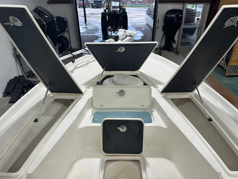 Slide: The Image of 2025 Key West 230BR boat with open storage compartments in a garage setting. - 42