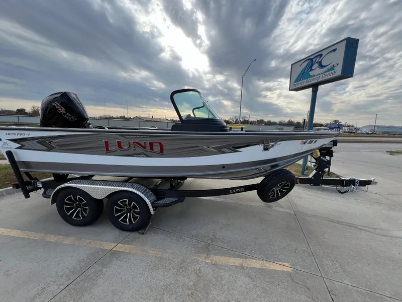 Slide: The Image of 2024 Lund 1875 Pro-V boat on trailer, parked outdoors under cloudy sky. - 3