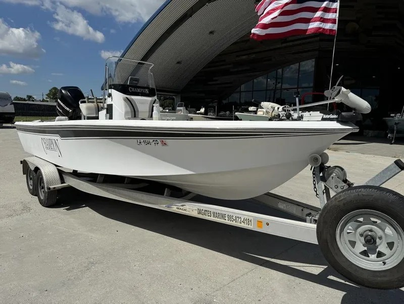 Slide: The Image of 2007 Champion 220 Bay boat on trailer with American flag, parked outdoors. - 10