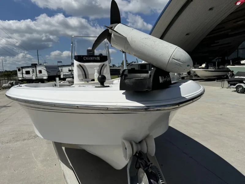 Slide: The Image of 2007 Champion 220 Bay boat with trolling motor, parked outdoors under a cloudy sky. - 9
