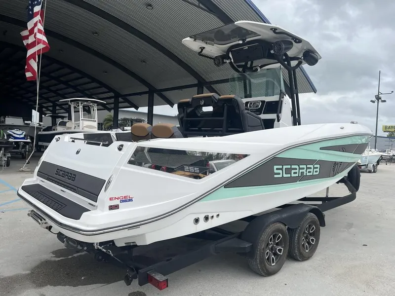 Slide: The Image of 2022 Scarab 255 Open ID boat on trailer, displayed outdoors under a canopy. - 12