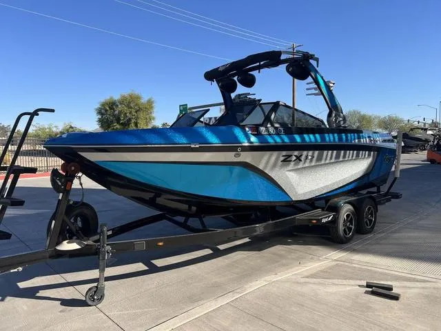 Slide: The Image of 2020 Tigé 23ZX boat on trailer, blue and black design, parked outdoors. - 4