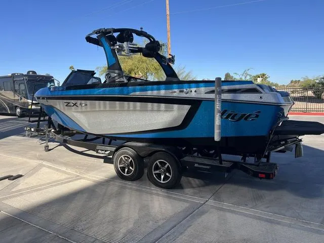 Slide: The Image of 2020 Tigé 23ZX boat on trailer, blue and silver, parked outdoors. - 6