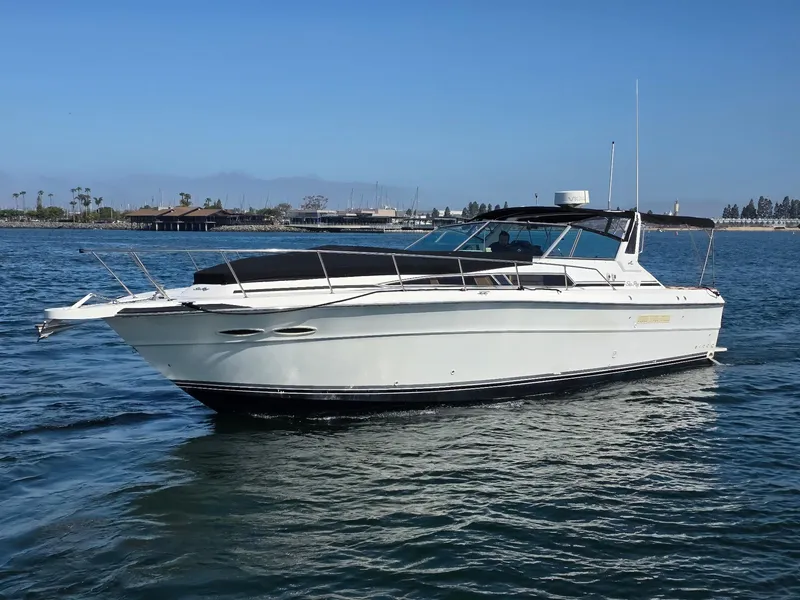 The Image of 1988 Sea Ray 390 Express Cruiser on calm water, clear sky background. - 0