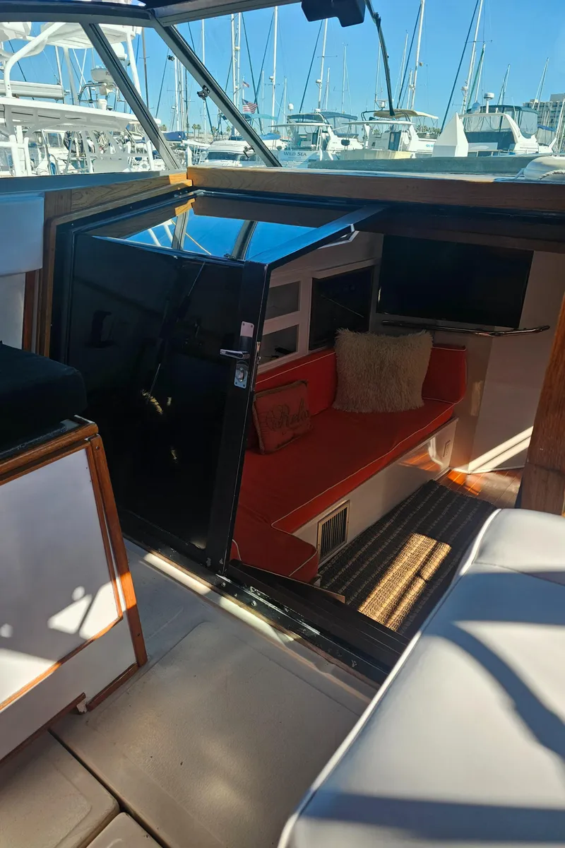 Slide: The Image of 1988 Sea Ray 390 Express Cruiser interior with red seating and marina view. - 7