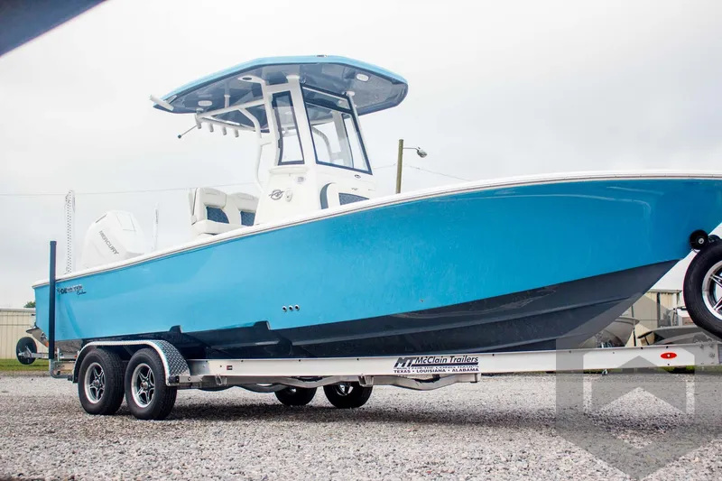 Slide: The Image of 2025 Tidewater 2500 Carolina Bay boat on trailer, vibrant blue hull, parked outdoors. - 9