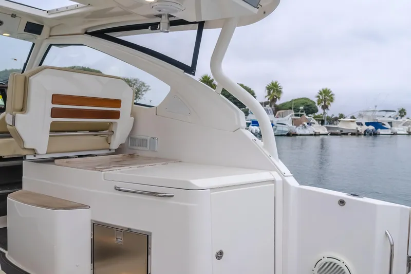 Slide: The Image of 2018 Pursuit 365 DC boat interior with seating and storage, docked at a marina. - 14