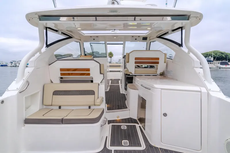 Slide: The Image of 2018 Pursuit 365 DC boat interior with seating and cabinetry, docked at a marina. - 18