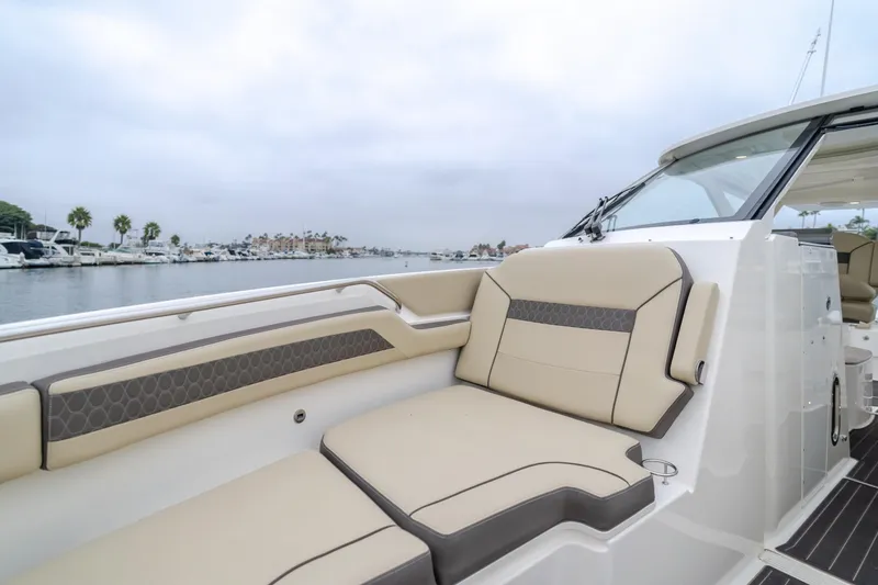 Slide: The Image of 2018 Pursuit 365 DC boat interior with beige seating, docked by a marina. - 30