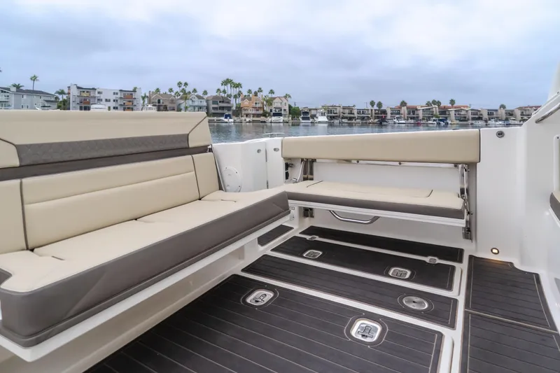 Slide: The Image of 2018 Pursuit 365 DC boat interior with beige seating and waterfront view. - 35