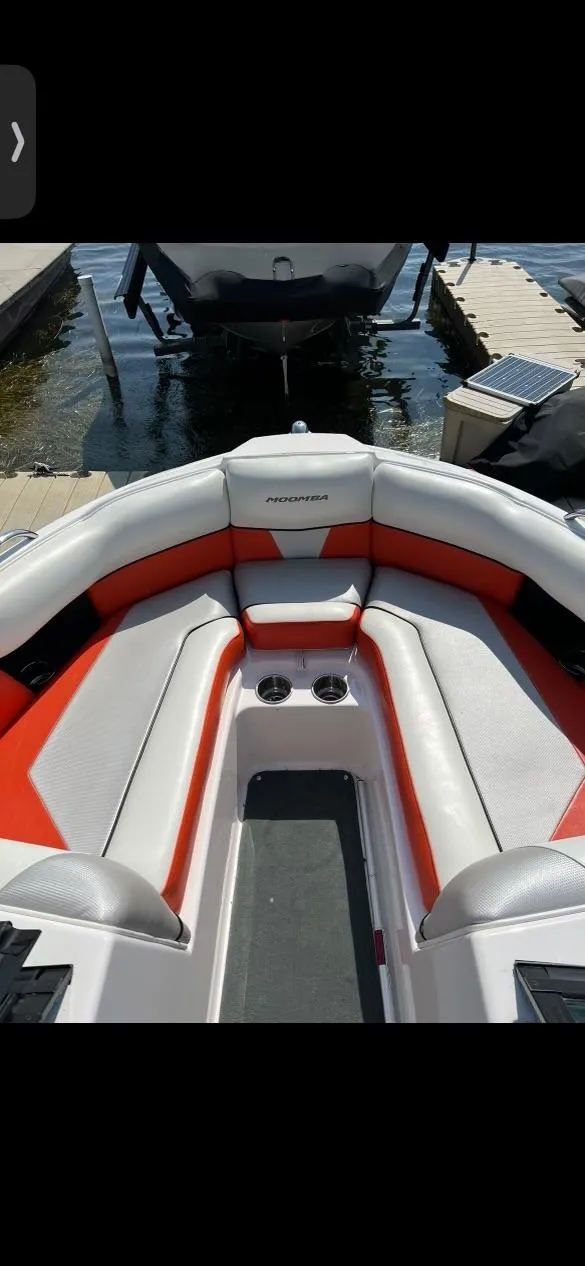 Slide: The Image of 2014 Moomba Mondo boat interior with red and gray seating, docked by the water. - 7