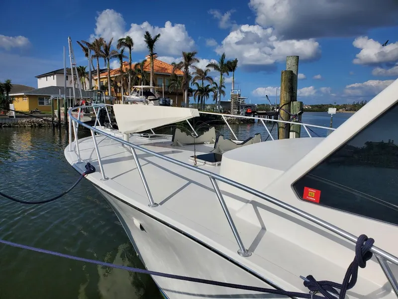 Slide: The Image of 1988 Post 46 Sportfish boat docked by waterfront homes under a blue sky. - 3