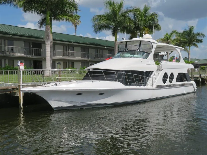 Slide: The Image of 2000 Bluewater Yachts Millennium Series 63 docked by palm trees and a building. - 0