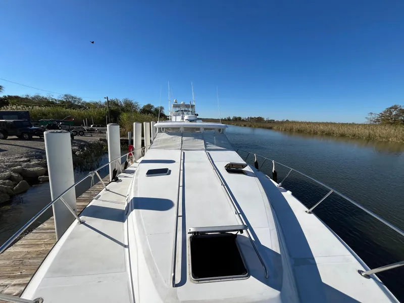 Slide: The Image of 1987 Sea Ray 460 yacht docked by a serene river under a clear blue sky. - 5