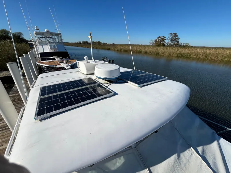 Slide: The Image of 1987 Sea Ray 460 yacht with solar panels docked on a calm river. - 9