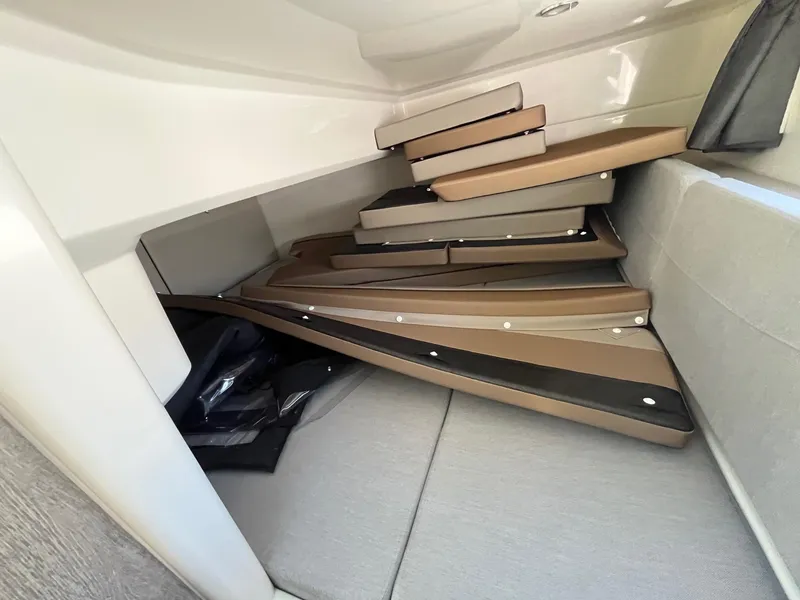 Slide: The Image of 2025 Bayliner Trophy T29 Explorer interior with stacked cushions in cabin. - 18