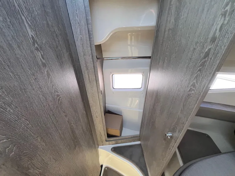 Slide: The Image of 2025 Bayliner Trophy T29 Explorer cabin interior with wood finish and window. - 22