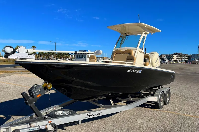 Slide: The Image of 2018 Scout 251 XSS boat on trailer in sunny parking lot. - 2