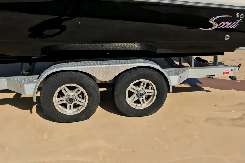 Slide: The Image of 2018 Scout 251 XSS boat on trailer with dual wheels, parked on sandy ground. - 20