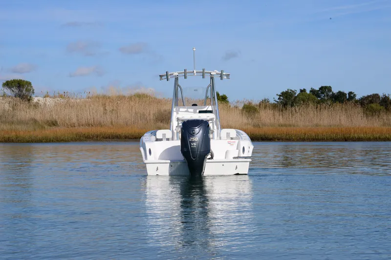 Slide: The Image of 2024 Contender 24 Sport boat on calm water, surrounded by reeds and clear sky. - 12