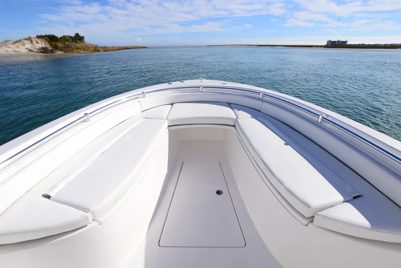 Slide: The Image of 2024 Contender 24 Sport boat on calm water, featuring spacious seating and clear skies. - 14