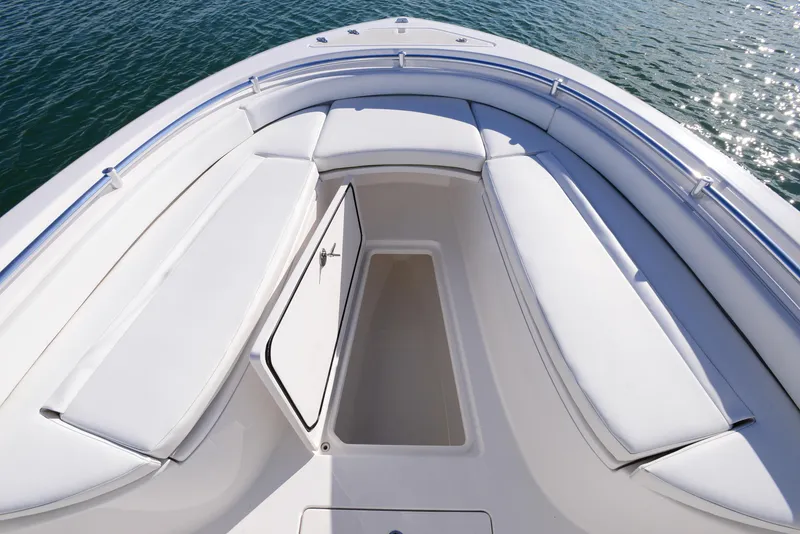 Slide: The Image of 2024 Contender 24 Sport boat interior with open storage compartment, white seating, and ocean view. - 17