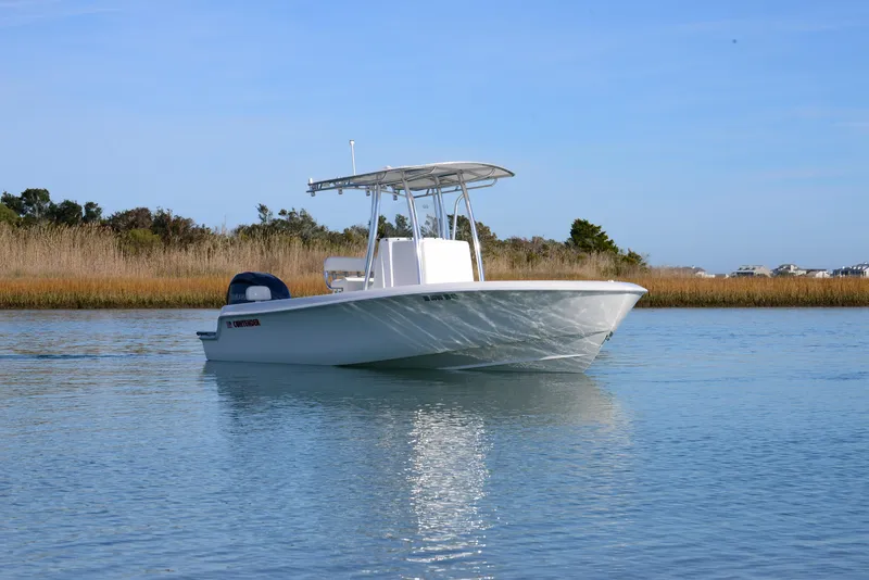 Slide: The Image of 2024 Contender 24 Sport boat on calm water, clear sky background. - 4