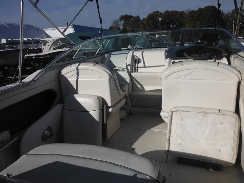 Slide: The Image of 2004 Sea Ray 215 Weekender boat interior with white seating and steering wheel. - 25