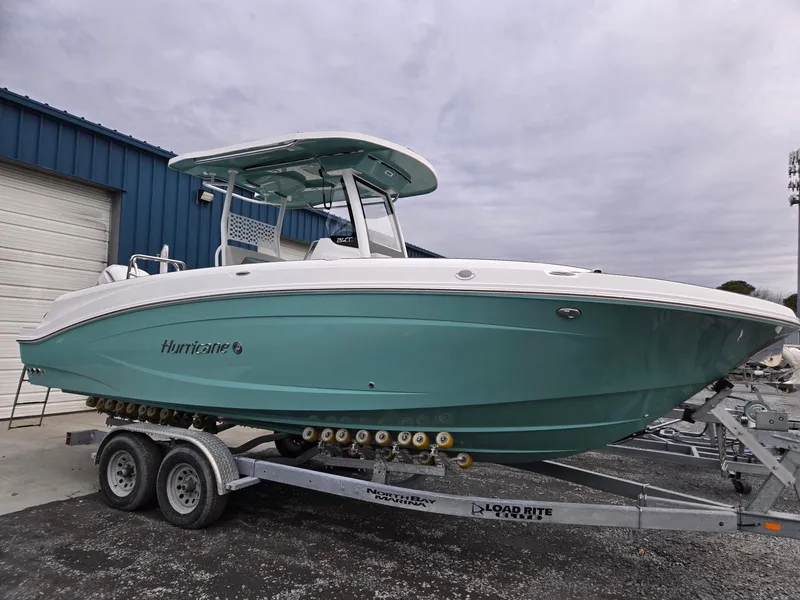 Slide: The Image of 2025 Hurricane Center Console 24 OB boat on trailer, teal hull, parked outdoors. - 0