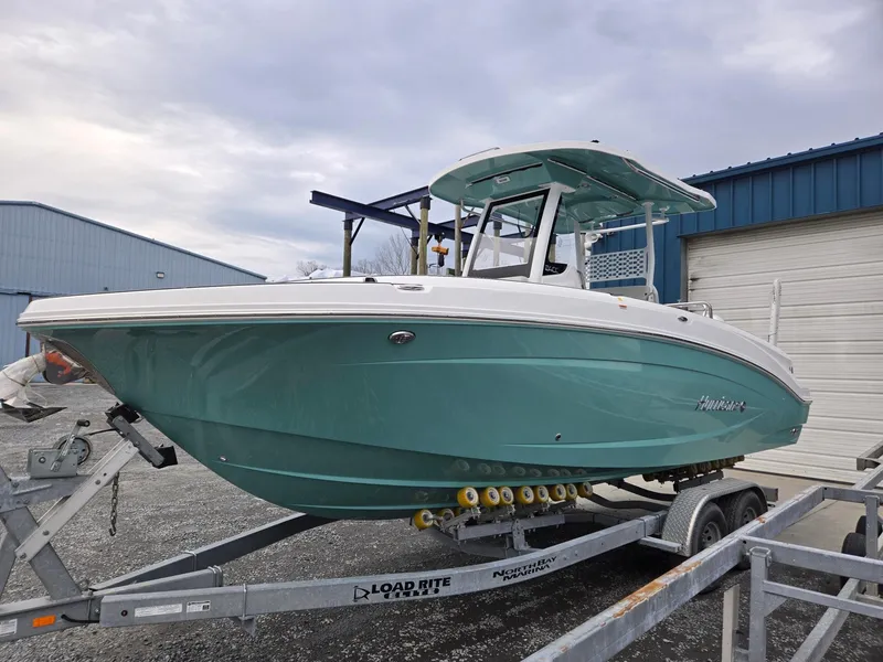Slide: The Image of 2025 Hurricane Center Console 24 OB boat on trailer, teal hull, parked outdoors. - 6