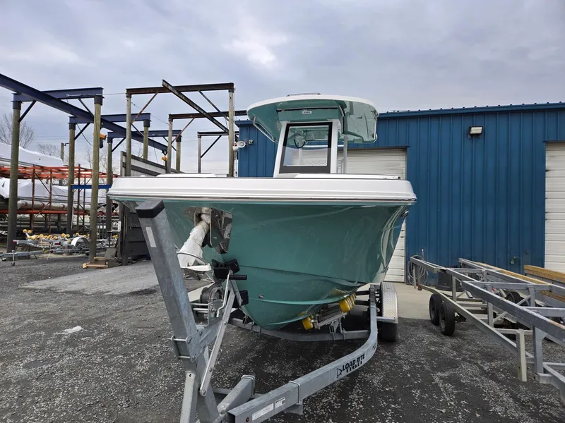 Slide: The Image of 2025 Hurricane Center Console 24 OB boat on trailer, parked near blue building. - 7