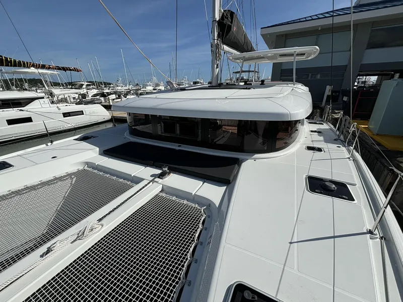 Slide: The Image of 2025 Lagoon 42 catamaran docked at marina, showcasing sleek design and spacious deck. - 18