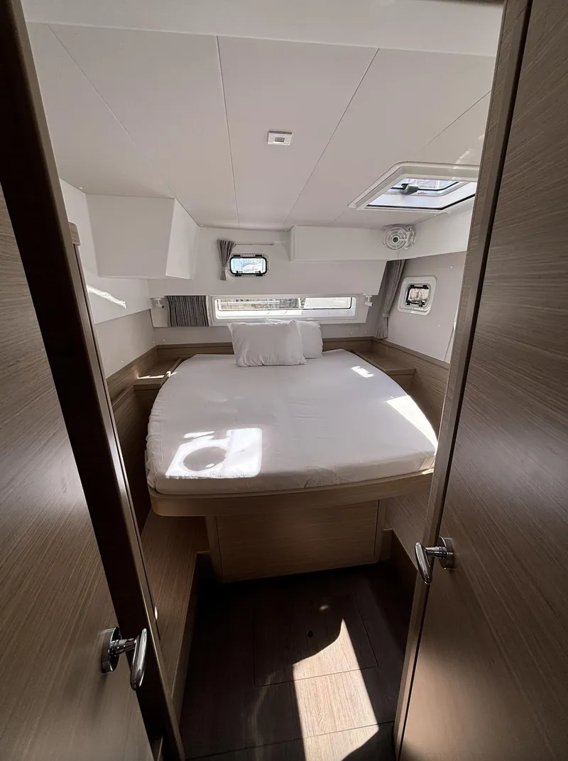 Slide: The Image of 2025 Lagoon 42 yacht cabin interior with bed and windows. - 22
