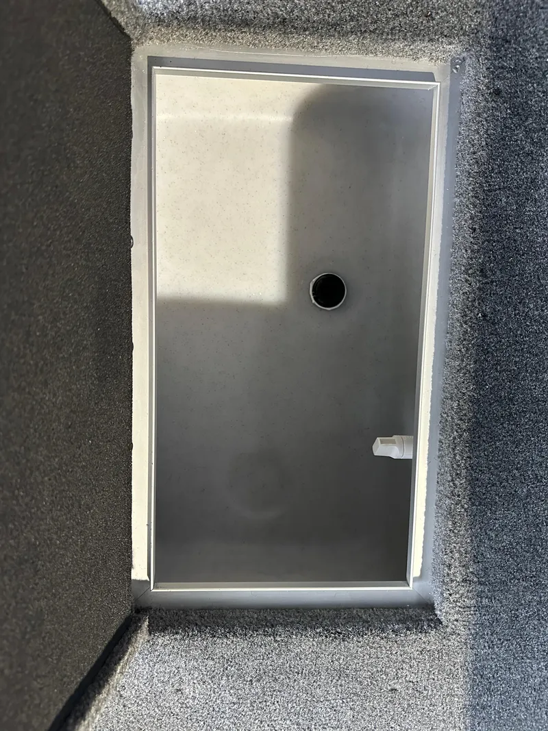 Slide: The Image of 2025 Smoker Craft Adventurer 188 DC storage compartment with drain hole. - 13