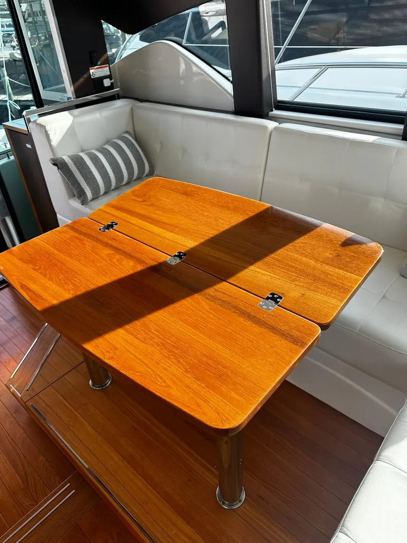 Slide: The Image of Interior of 2016 Tiara Yachts 49 COUPE with wooden table and white seating. - 16