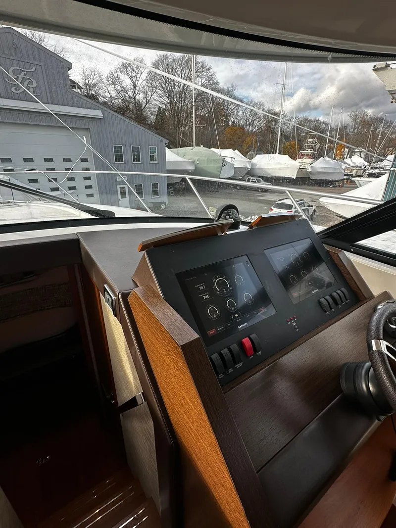 Slide: The Image of 2016 Tiara Yachts 49 COUPE helm with modern controls and marina view. - 45
