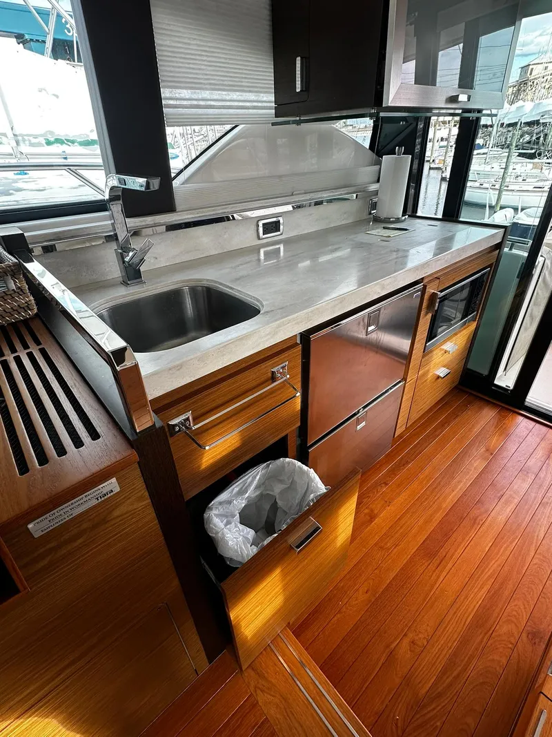Slide: The Image of 2016 Tiara Yachts 49 COUPE kitchen with stainless steel appliances and wooden flooring. - 47