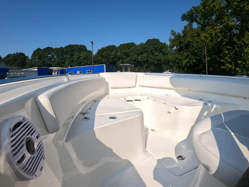Slide: The Image of 2025 Key West 239 FS boat interior with white seating and speaker, surrounded by trees. - 14
