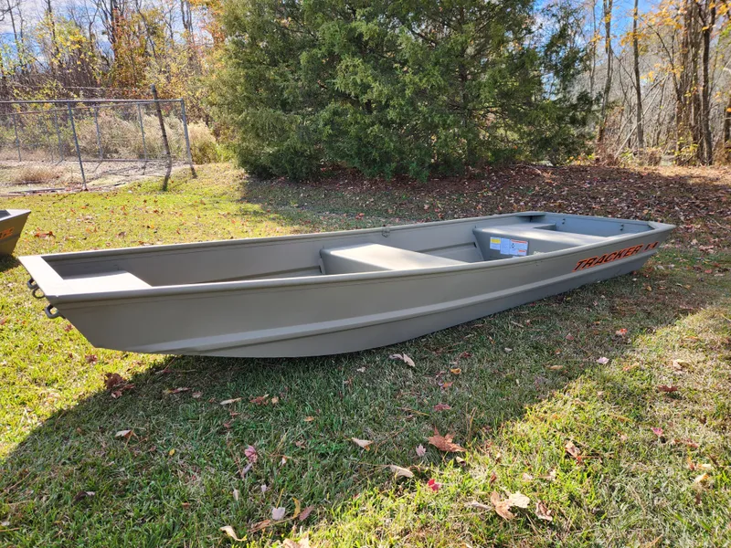 The Image of 2025 Tracker Grizzly 1436 Utility boat on grass, surrounded by trees. - 0