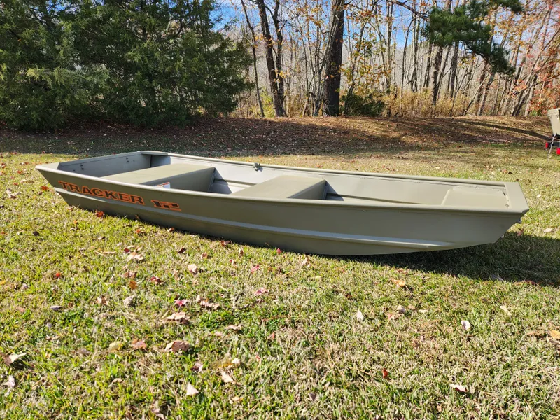 The Image of 2025 Tracker Grizzly 1236 Utility boat on grassy field, surrounded by trees. - 0