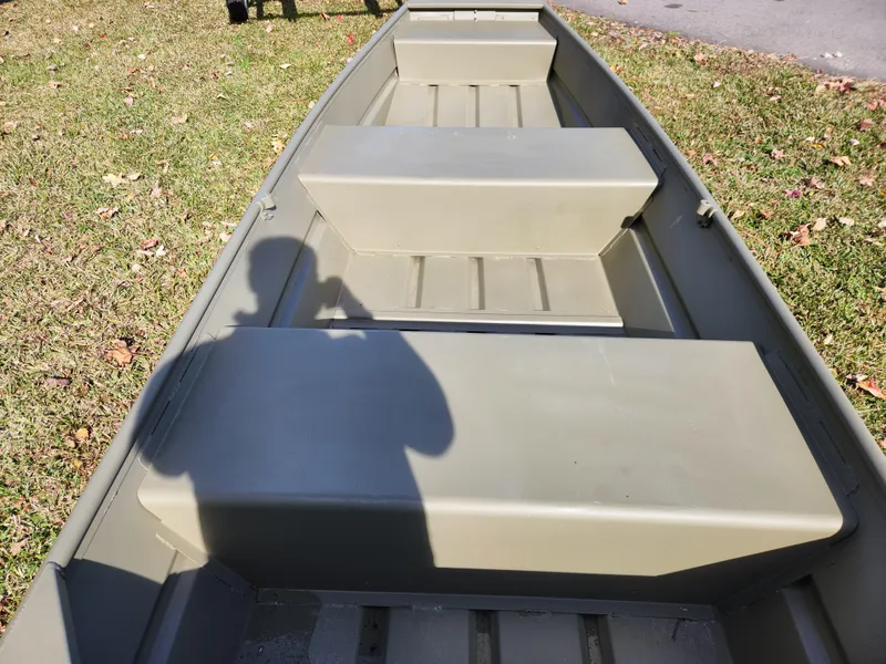 Slide: The Image of 2025 Tracker Grizzly 1236 Utility boat on grass, showing interior seating and shadow. - 3