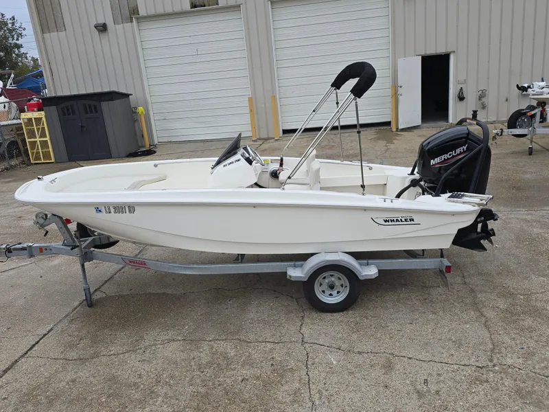 Slide: The Image of 2022 Boston Whaler 160 Super Sport boat on trailer, parked outside a garage. - 8