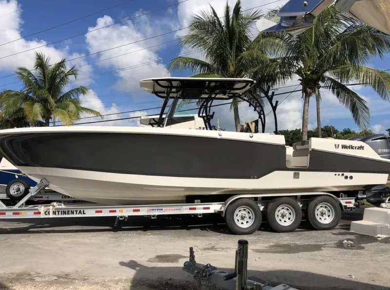 Slide: The Image of 2018 Wellcraft 302 Fisherman boat on trailer, parked under palm trees. - 0